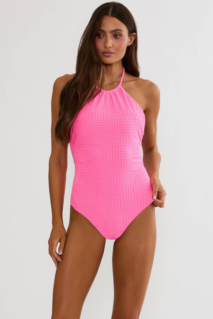 Woman wearing a bright pink halter neck swimsuit on a white background
