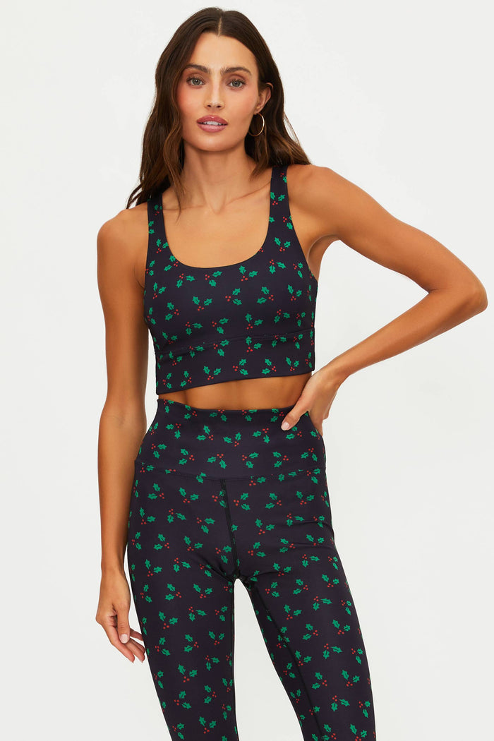 Woman wearing a navy blue sports bra and leggings with green leaf pattern on a white background