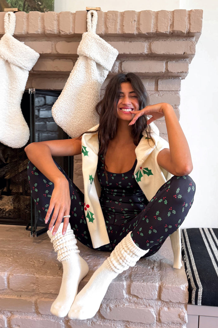 Woman wearing a black sports bra and leggings with green holly