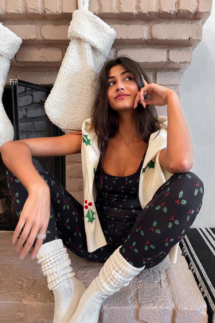 Woman wearing a black sports bra and leggings with green holly