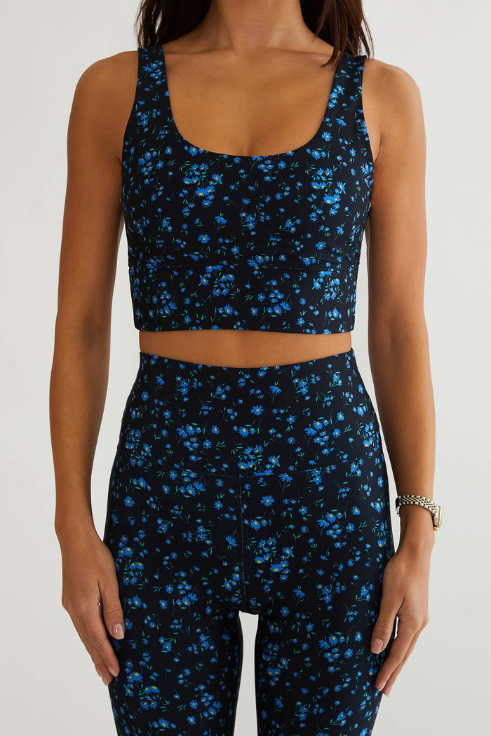 Woman wearing black with blue floral workout bra.