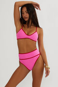 Woman wearing a pink and red swimsuit against a plain background