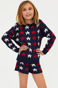A child wearing a long sleeve navy blue sweater with a pattern of white and red stars.