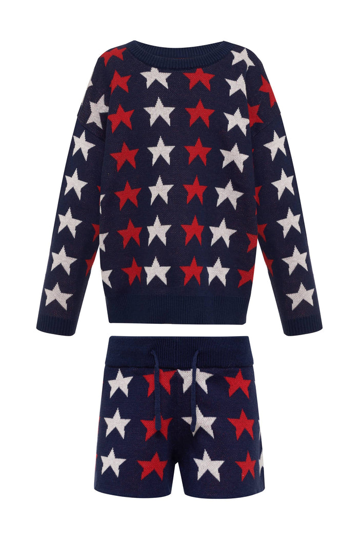 A child wearing a long sleeve navy blue sweater with a pattern of white and red stars.