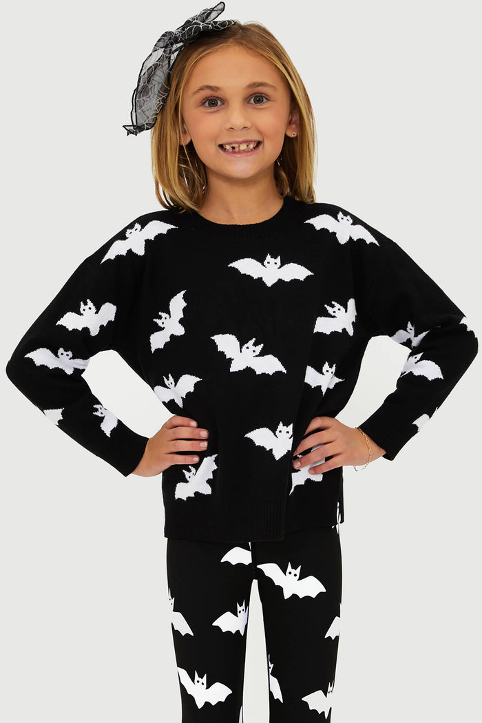 Child wearing a black outfit with white bat patterns on a plain background