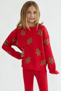 Child wearing a red sweater with gingerbread man patterns on a white background