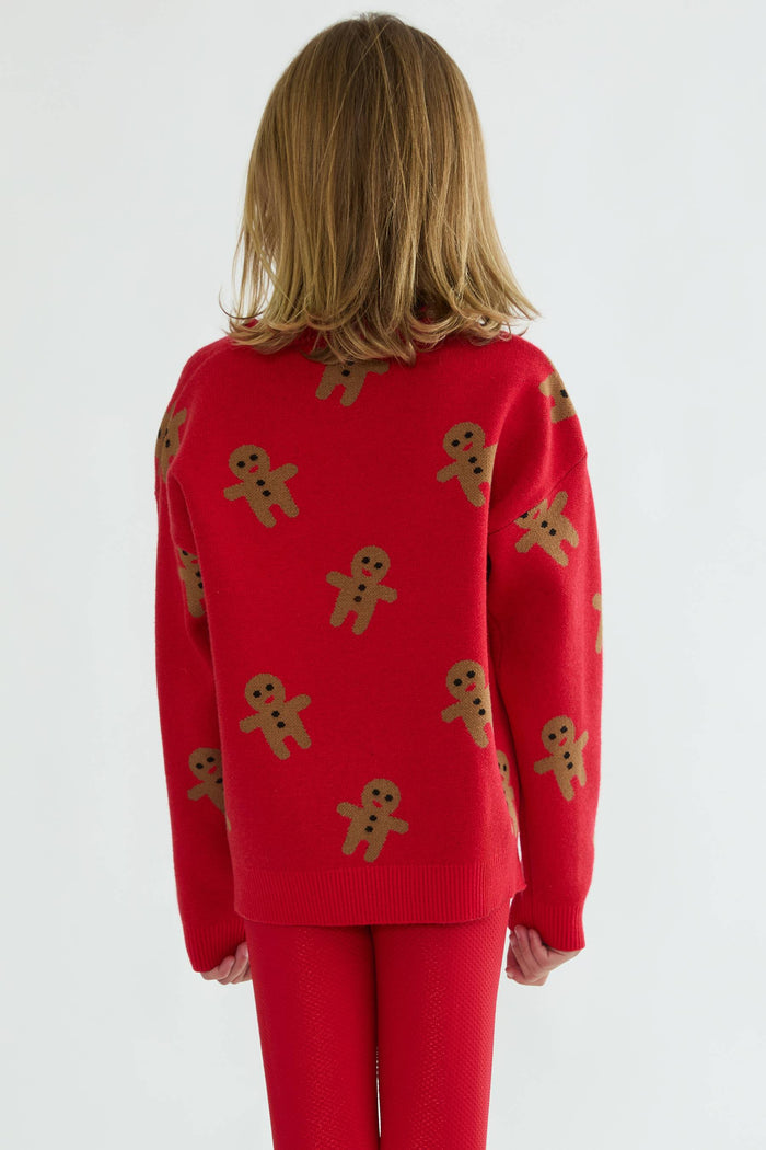 Person wearing a red sweater with gingerbread man patterns on a white background