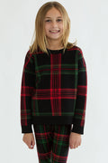 Child wearing a black and red plaid outfit on a white background