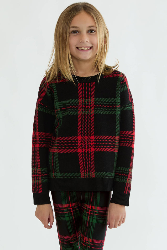 Child wearing a black and red plaid outfit on a white background