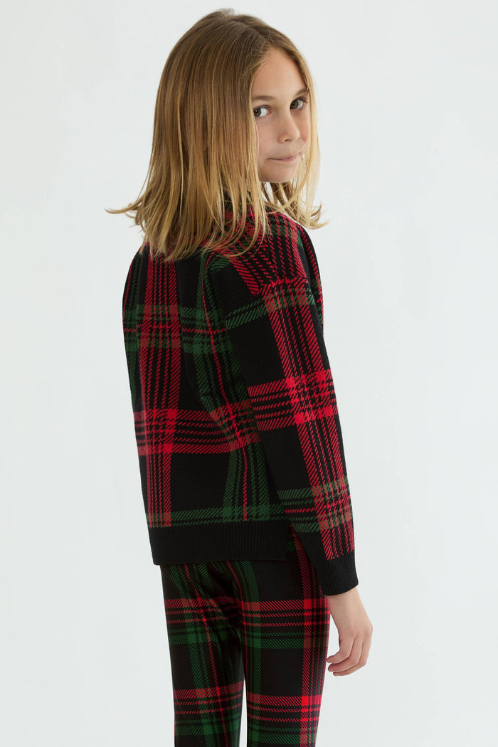 Child wearing a red and green plaid outfit on a white background