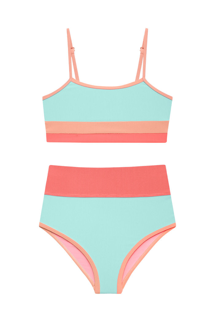 Young girl wearing a colorful two-piece swimsuit and sunglasses on a white background
