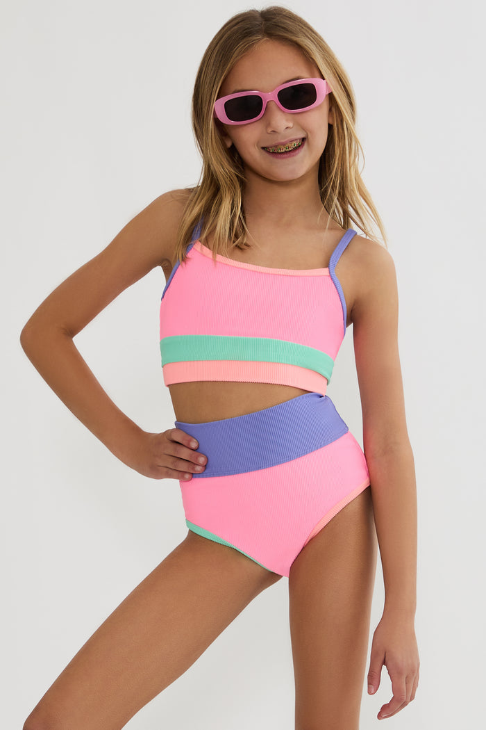 Young girl wearing a colorful two-piece swimsuit and sunglasses on a white background
