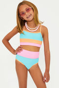 A child model wearing a two-piece swimsuit with horizontal color blocks in blue, pink, and orange, and white sunglasses