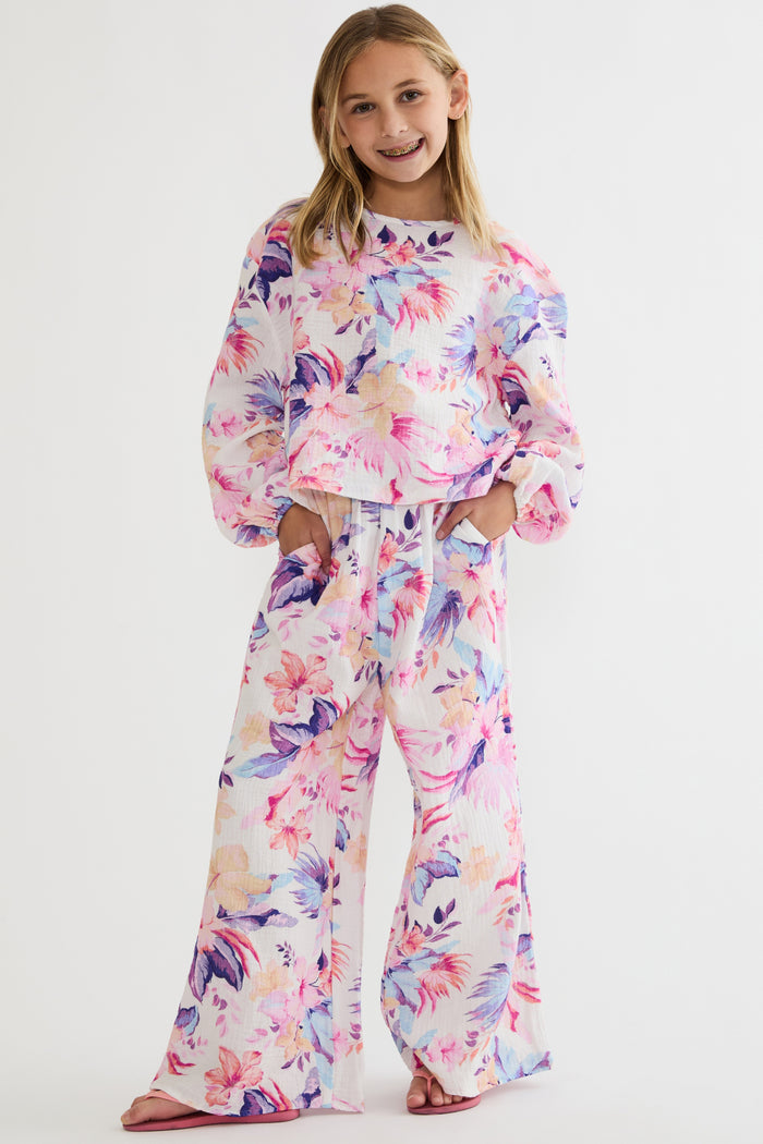 Young girl wearing a colorful floral outfit on a white background