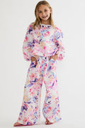 Young girl wearing a colorful floral outfit on a white background