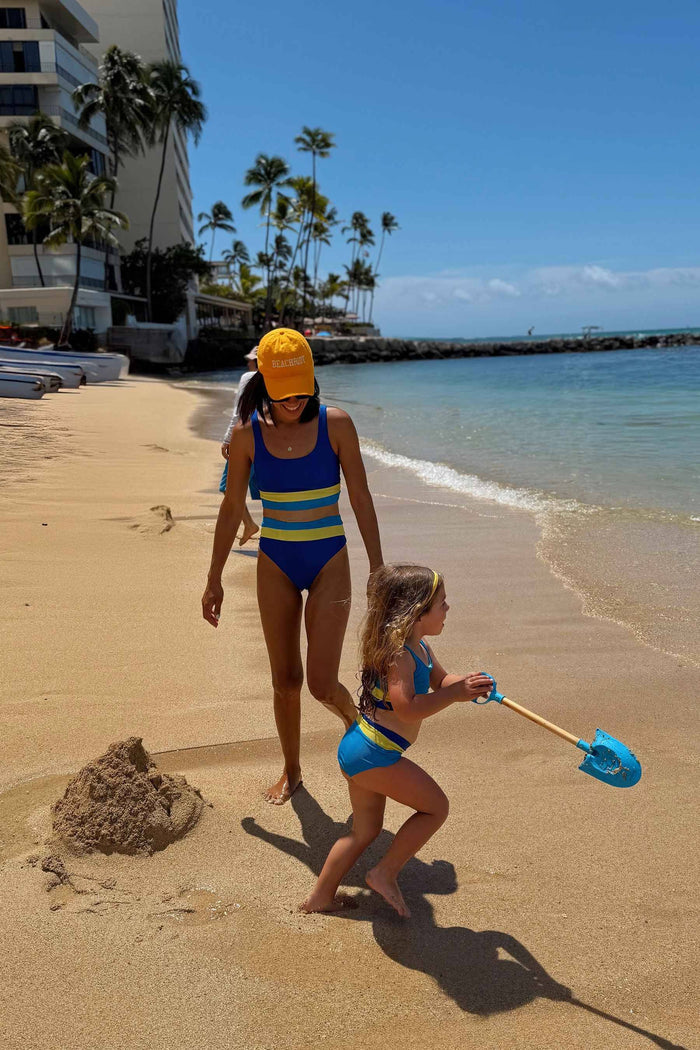 A child model wearing a two-piece swimsuit with a ribbed texture, featuring solid blue color with yellow and blue color blocks.
