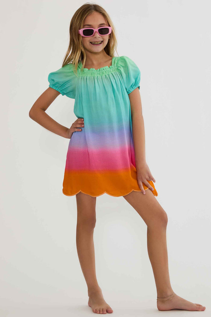 Young girl wearing a colorful dress with a gradient from green to orange on a white background