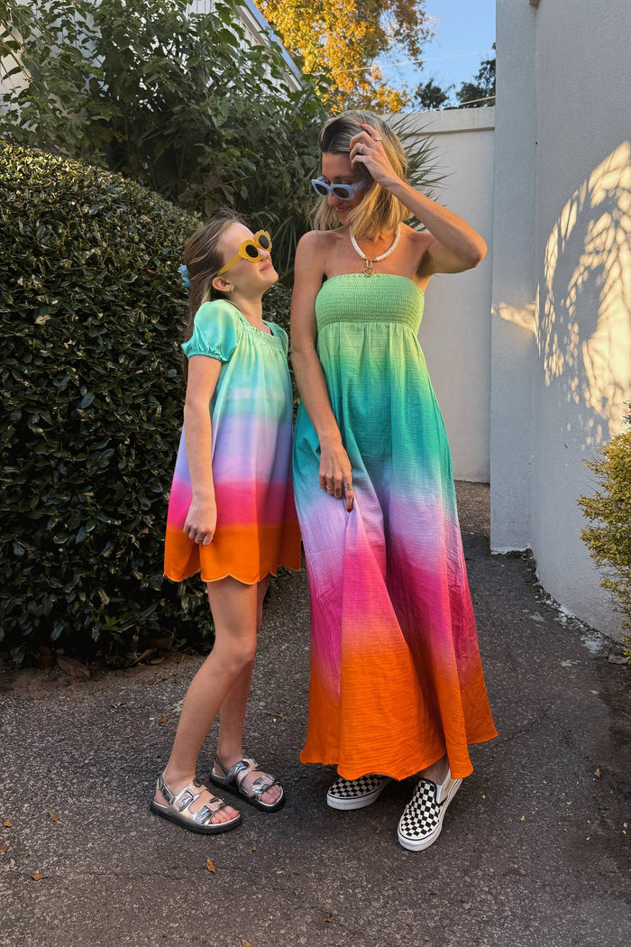 Two people wearing colorful dresses standing outdoors near a building.
