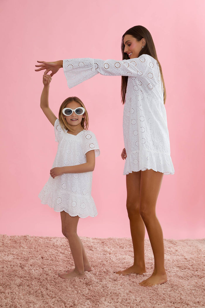 A model wearing a white short-sleeved dress with embroidered eyelet details and a square neckline.