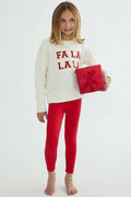 Young girl wearing a white sweater with 'FALA LAU' text and red leggings, holding a red gift box.