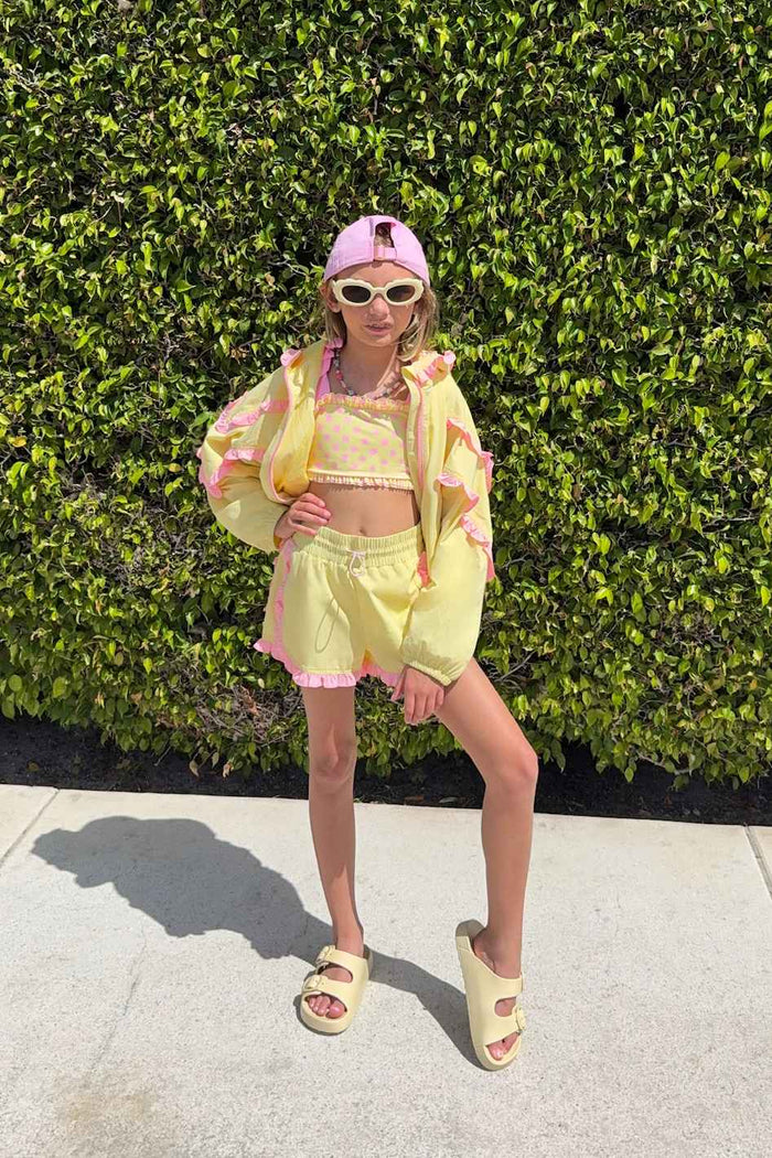 Kids yellow track shorts with pink ruffle lining.