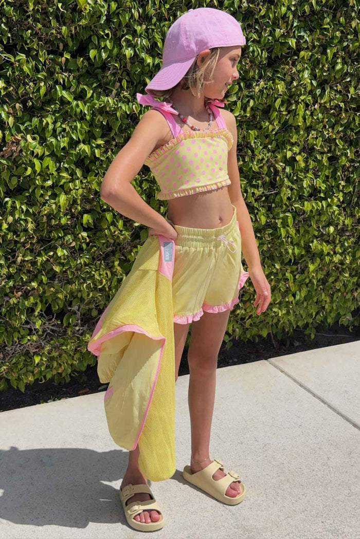 Kids yellow track shorts with pink ruffle lining.