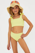 A young girl modeling a yellow high-waisted bikini bottom and a tankini top with bows on the shoulder straps, paired with a hat.