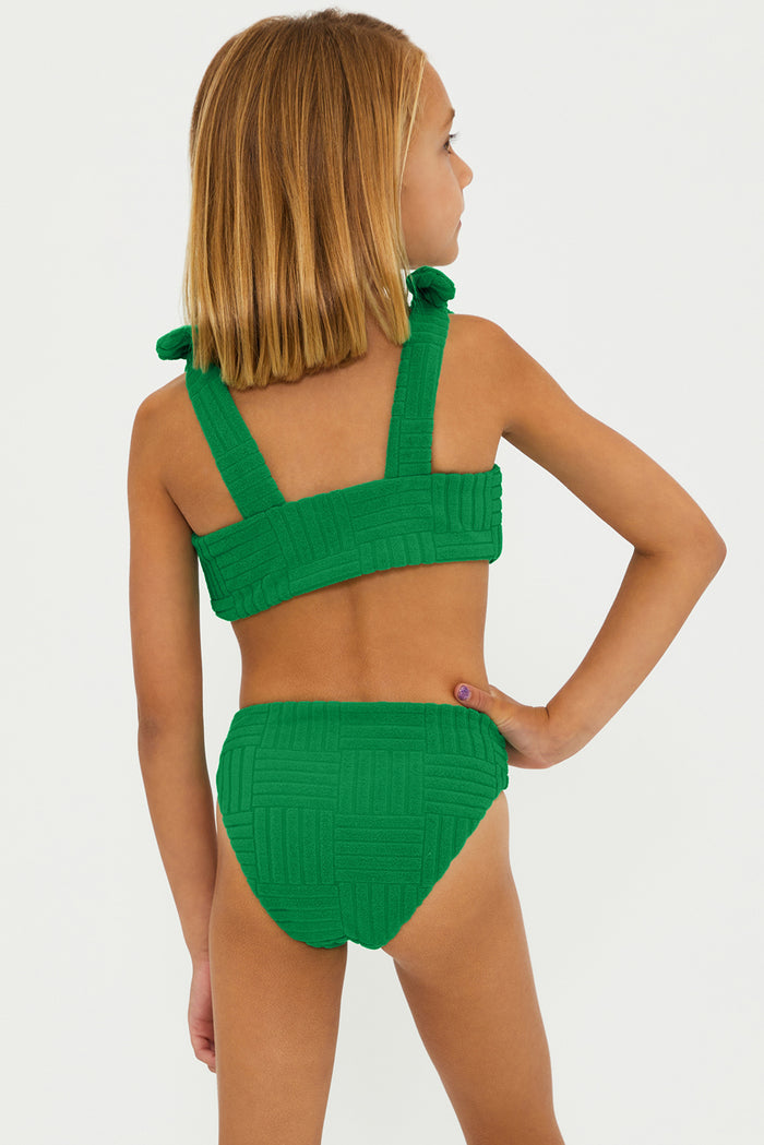 A girl wearing a two-piece swimsuit in Jelly Bean green color with bows on the straps.