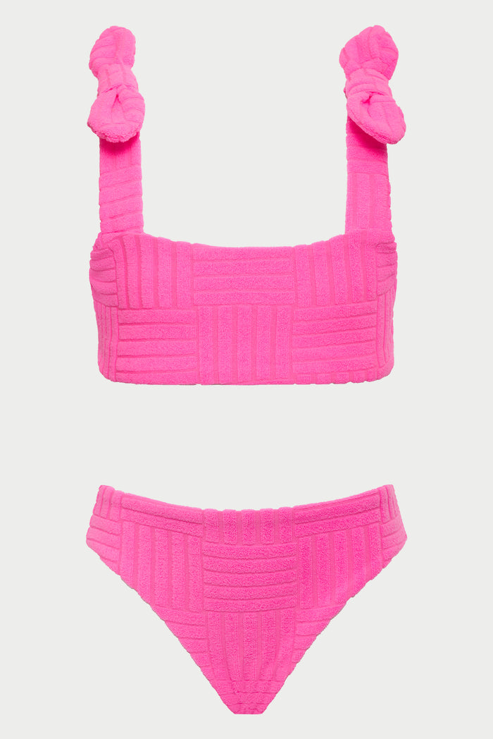 A young girl wearing a neon pink two-piece swimsuit with bows on the straps.