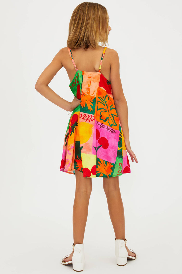 A young model wearing a sleeveless, multicolored floral dress with a square neckline and adjustable spaghetti straps.