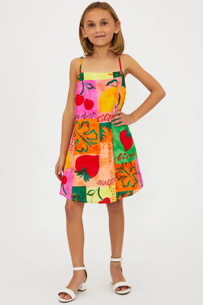 A young model wearing a sleeveless, multicolored floral dress with a square neckline and adjustable spaghetti straps.