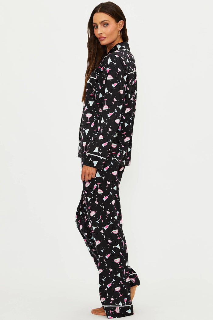 Woman wearing a black pajama set with pink flamingo pattern on a white background