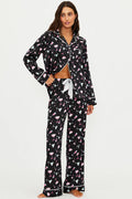 Woman wearing a black pajama set with flamingo pattern on a white background