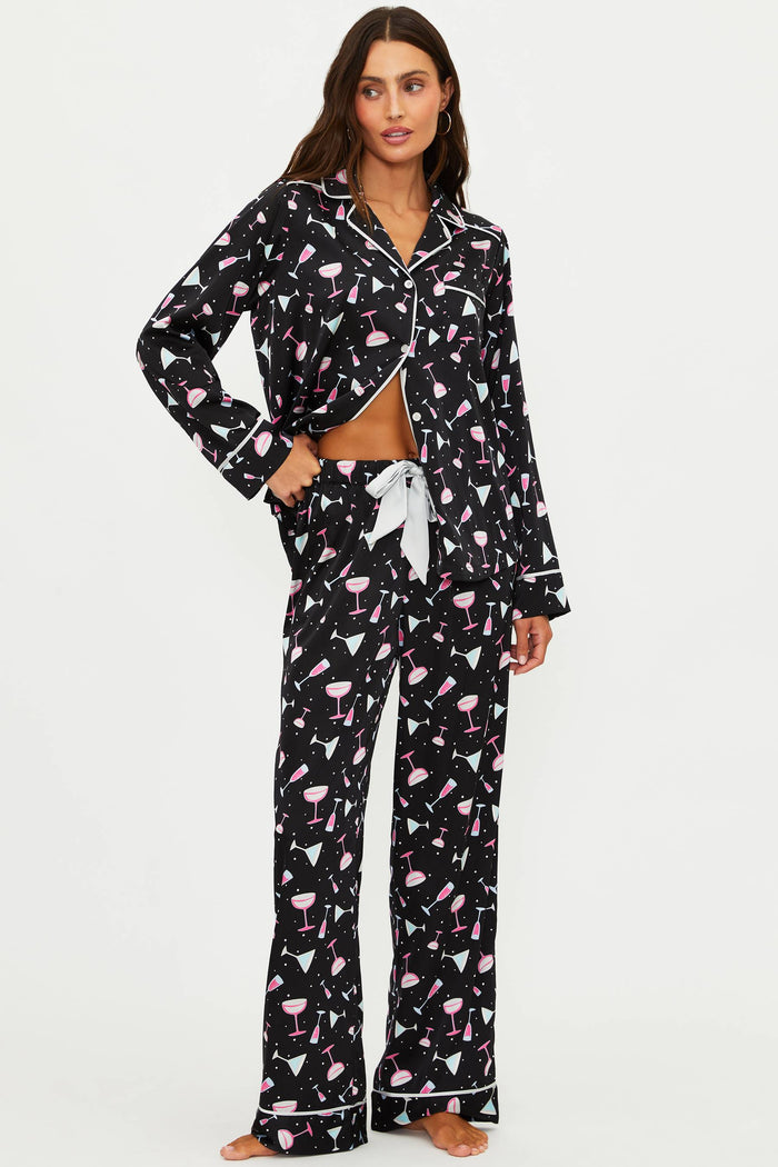 Woman wearing a black pajama set with flamingo pattern on a white background