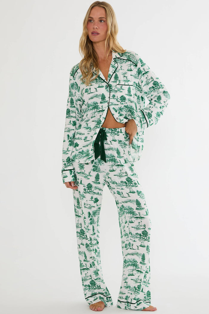 Woman wearing a green and white patterned pajama set on a white background