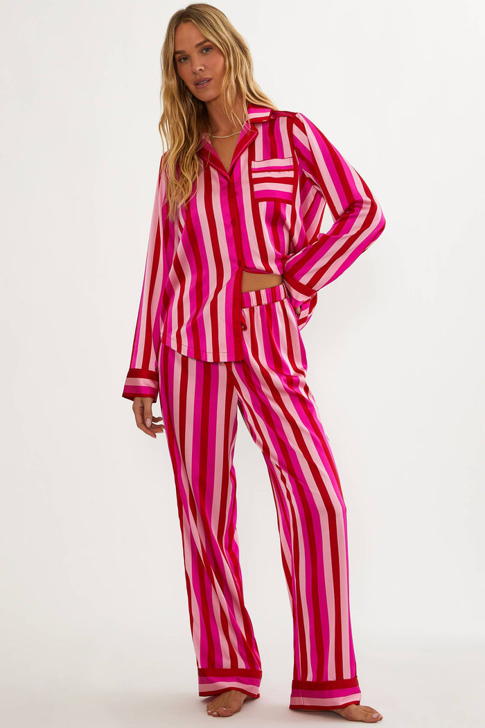 Woman wearing a pink and white striped pajama set on a white background