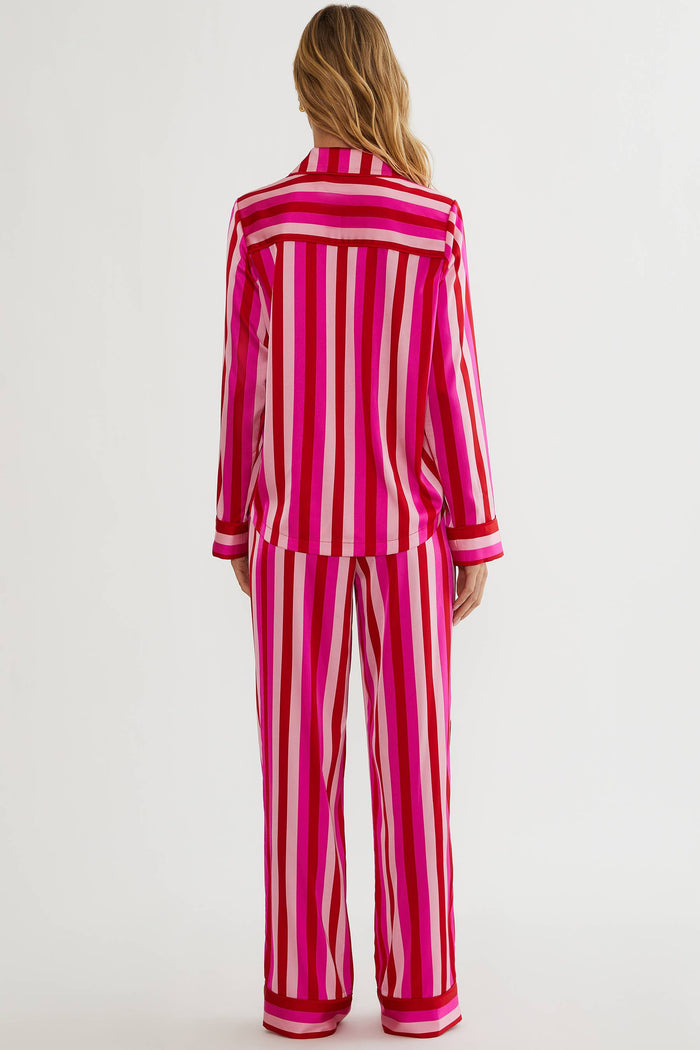 Person wearing a pink and white striped pajama set on a plain background