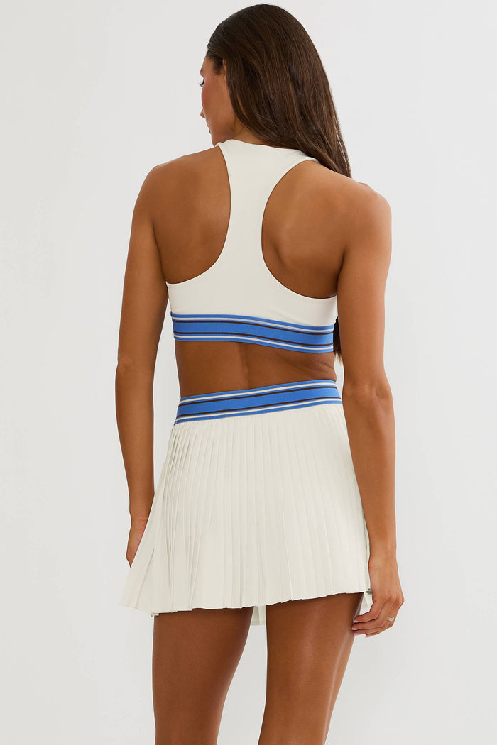 Woman wearing cream racerback sports bra with blue lining.