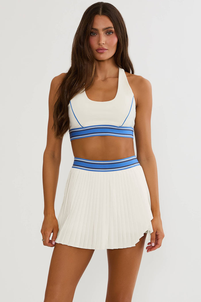 Woman wearing cream racerback sports bra with blue lining.