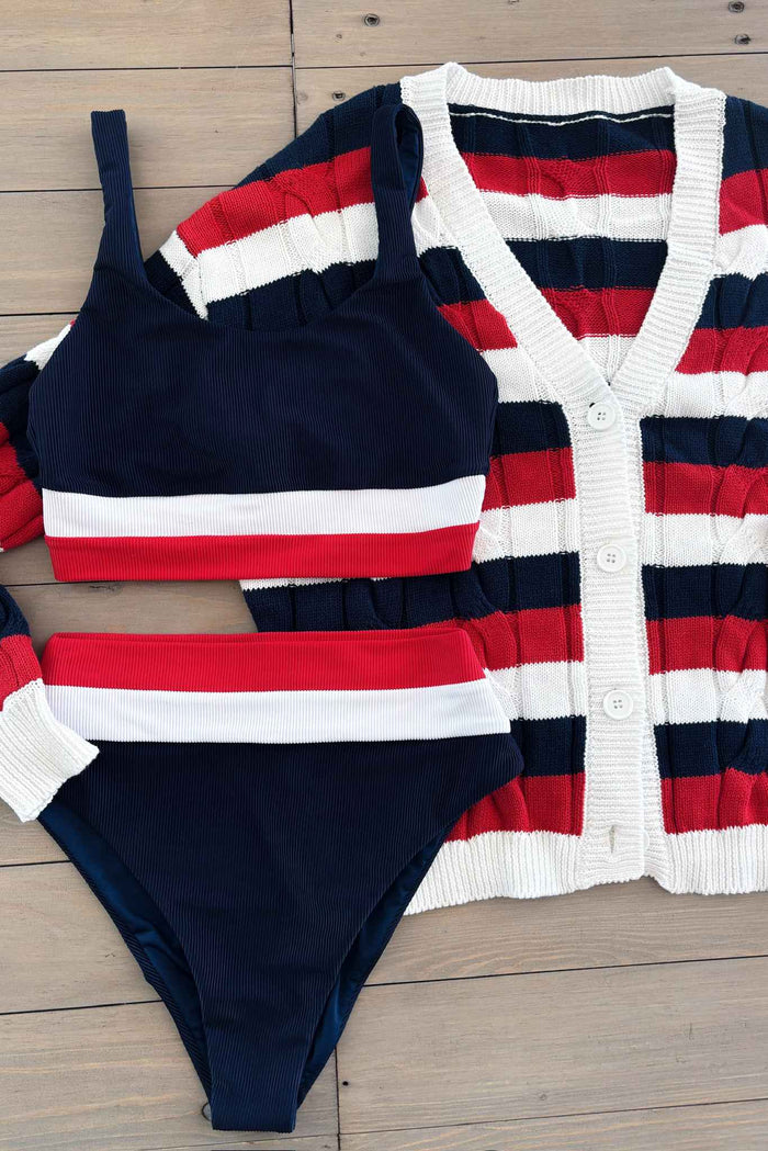 A woman wearing a navy blue swim top with red and white stripes at the chest and a matching bottom.