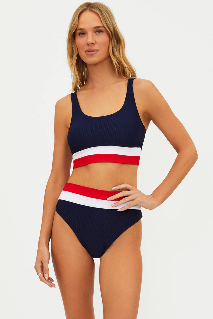 A woman wearing a navy blue swim top with red and white stripes at the chest and a matching bottom.