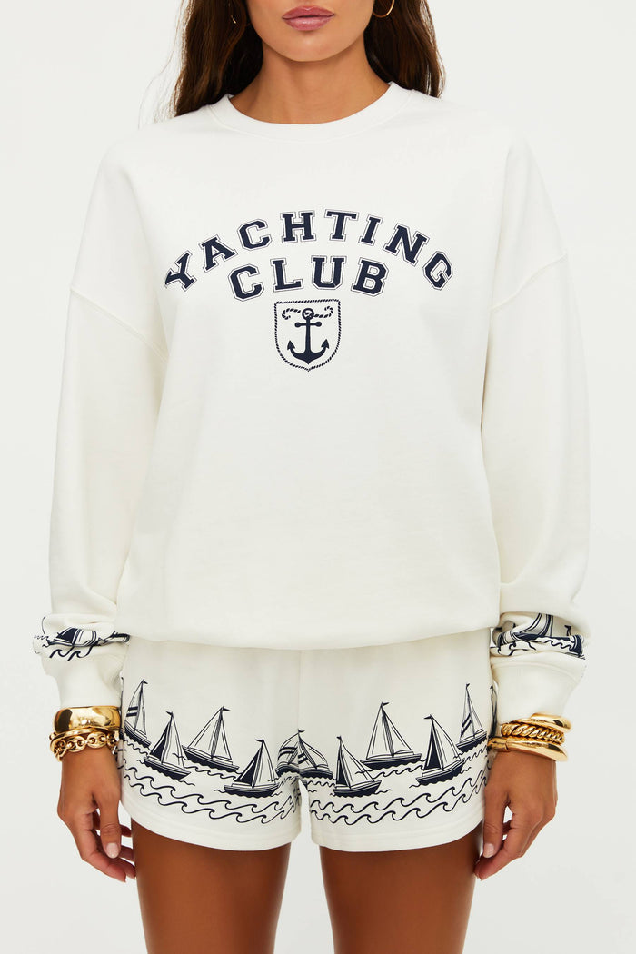 Person wearing a white 'Yachting Club' sweatshirt with sailboat designs on shorts.