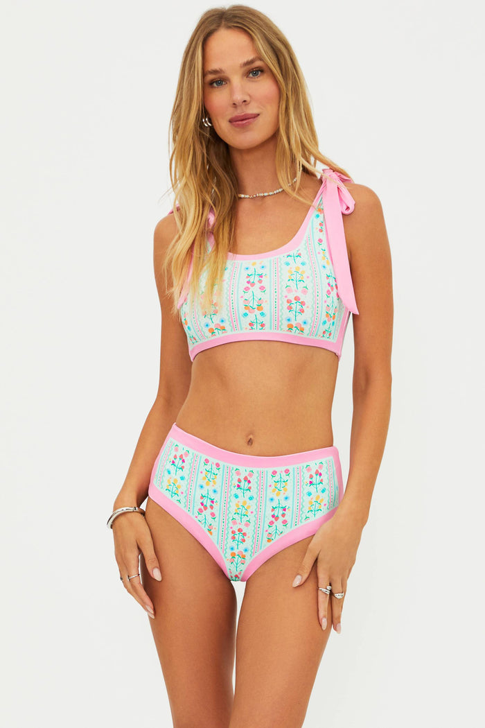 Woman wearing a colorful bikini set with floral patterns on a white background