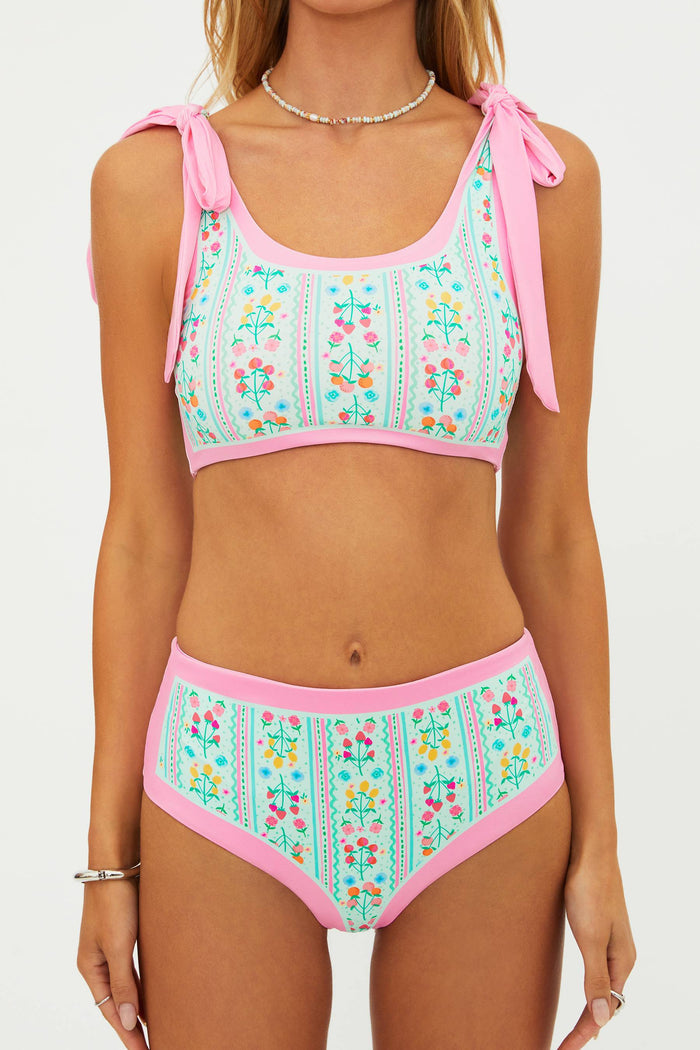 Woman wearing a floral bikini set with pink straps on a white background