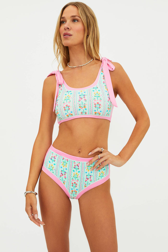 Woman wearing a colorful bikini with pink accents on a white background