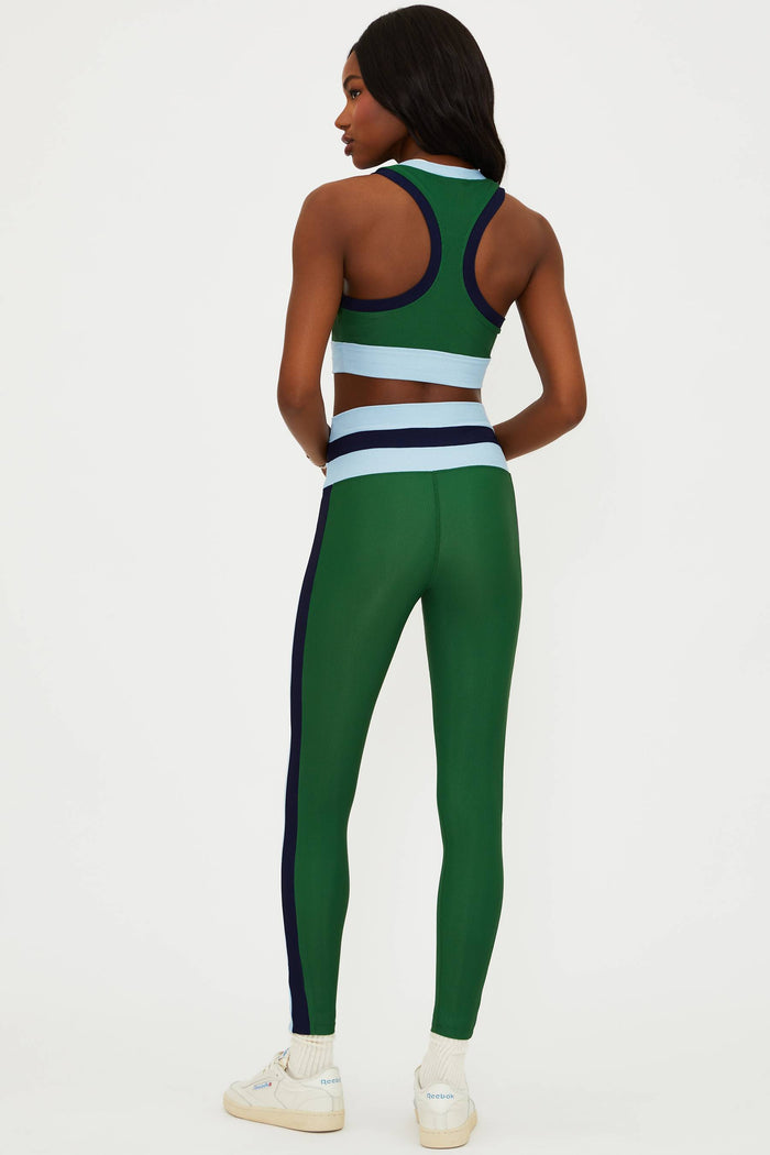 Person wearing a green athletic outfit with white sneakers on a white background