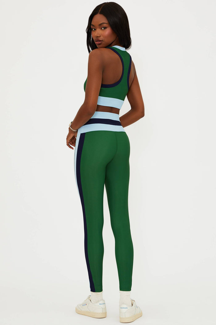 Person wearing a green sports outfit with white sneakers on a white background