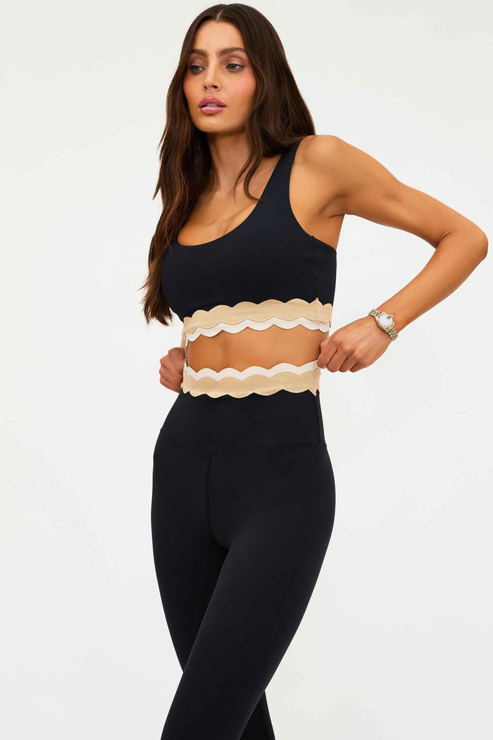 Woman wearing a black and beige top with black pants on a white background