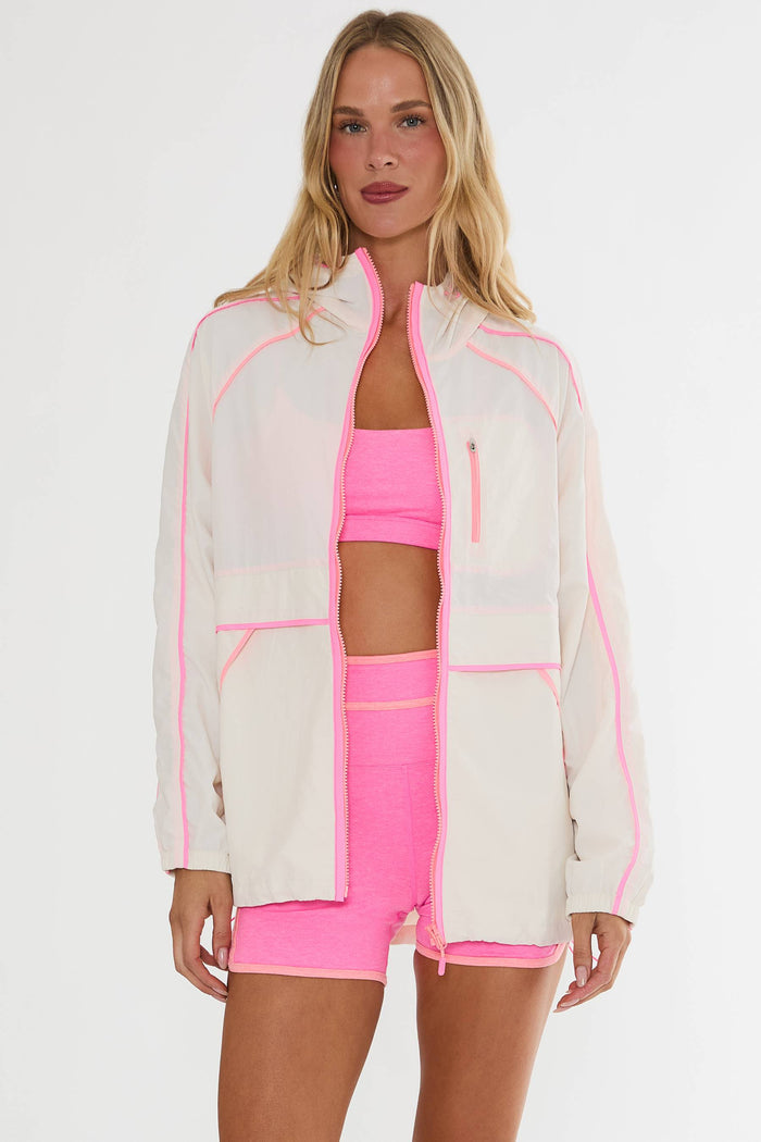 Woman wearing a white jacket with pink accents and matching pink athletic wear on a white background