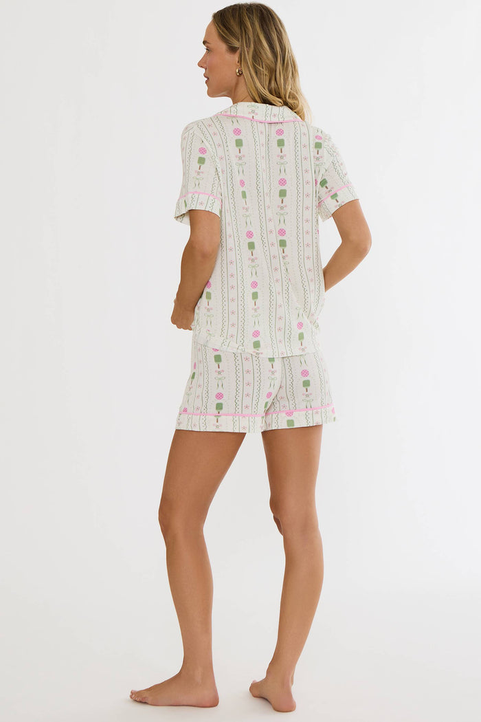 Woman wearing a white pajama set with floral patterns on a white background